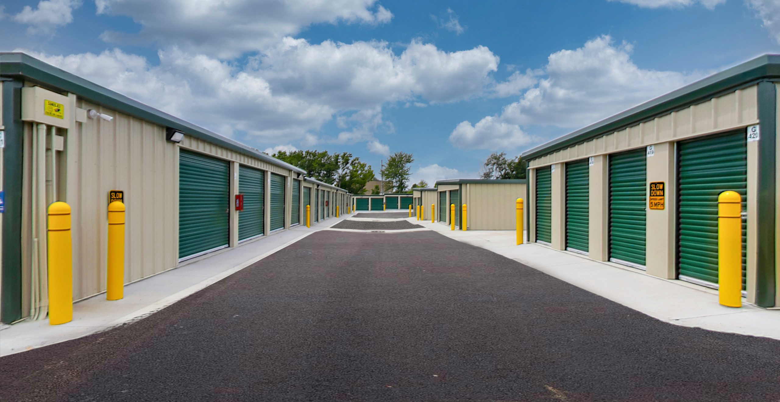 Rows of self-storage units with colorful doors, neatly aligned in a spacious facility, showcasing organized and secure storage solutions.